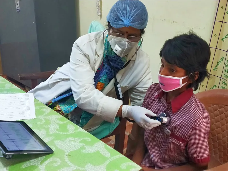 An Aarogya Vahini doctor examining a child during a mobile medical camp